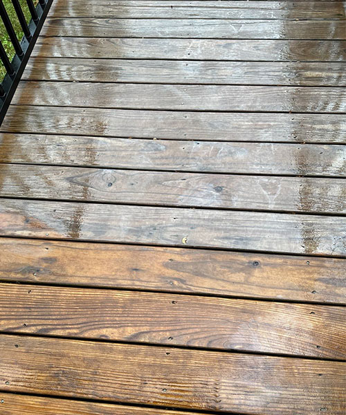 A dirty wooden deck is being power washed by a professional power washing company in Springfield, IL.