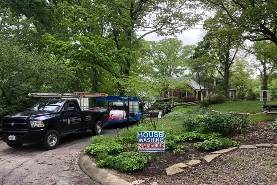 A commercial power washing truck with a trailer of professional equipment ready to safely power wash hard surfaces of a residential home in Springfield, IL.