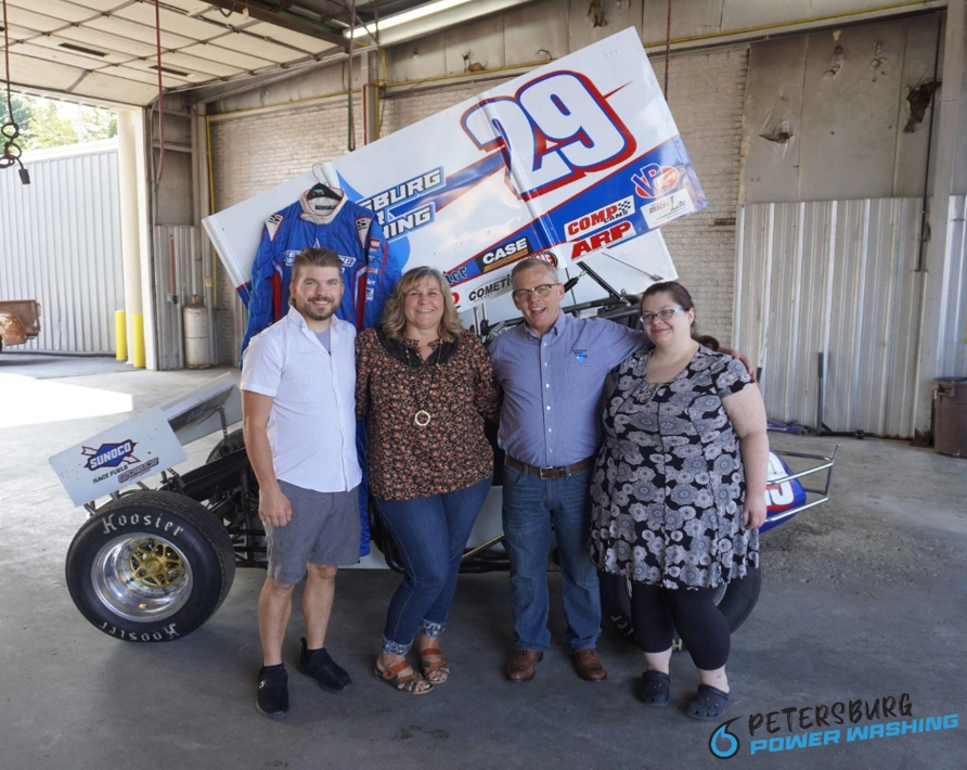 The Hillyer Family who own Petersburg Power Washing standing in front of a sprint car.